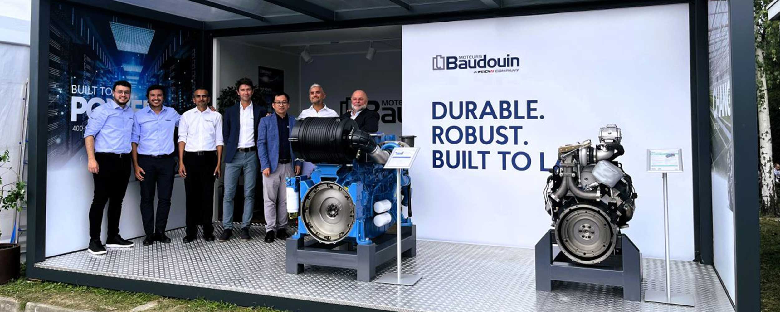 Moteurs Baudouin employees stood on an exhibition stand next to two Baudouin engines.